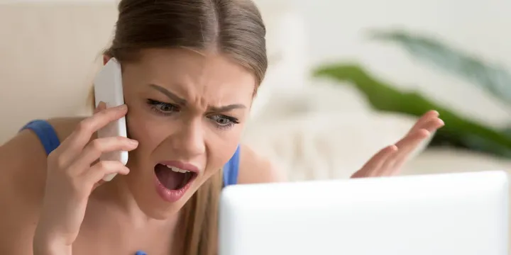 Woman screaming on the phone, looking dismayed.
