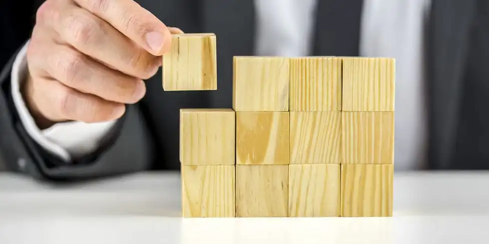 Someone putting a wooden block next to other wooden blocks