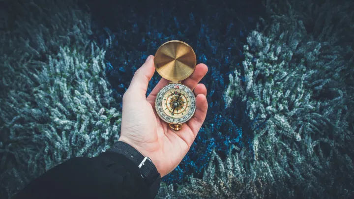 A hand holding a compass